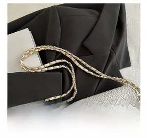 Détail du sac gris en cuir croco avec une élégante bandoulière en chaîne dorée tressée