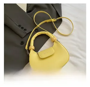 Detail view of yellow half-moon dumpling bag with rounded handle and sphere decor