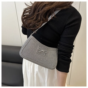Sac à bandoulière argenté scintillant avec nœud porté par une femme en noir et blanc