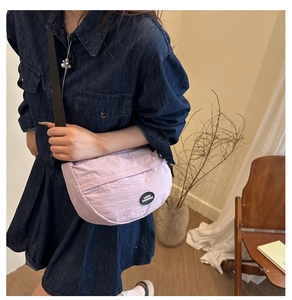 Dettaglio borsa a mezzaluna in nylon lavanda con tracolla regolabile nera indossata da modella
