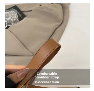 Close-up of caramel leather shoulder strap with neat stitching and litchi grain texture
