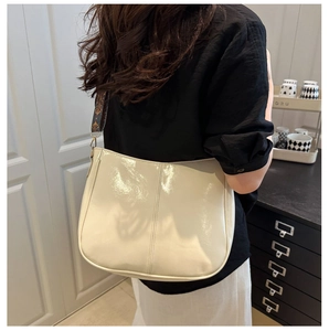 Detail of cream patent leather tote bag with stylish patterned wide shoulder strap