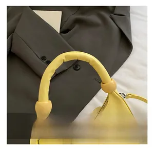 Detail of yellow crescent bag with padded handle and decorative oversized tonal beads