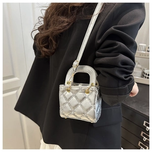 Detail of silver metallic quilted mini handbag featuring gold hardware and adjustable strap