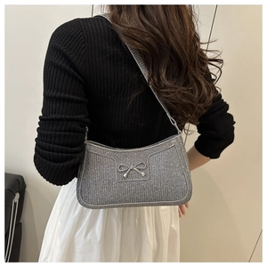 Silver sequin shoulder bag with metallic bow detail styled on woman's shoulder