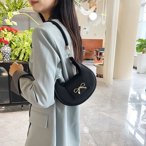 Elegante borsa a spalla a mezzaluna nera con fiocco dorato e blazer grigio