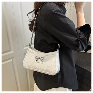 Détail du sac à bandoulière blanc à motif crocodile avec décoration nœud argenté