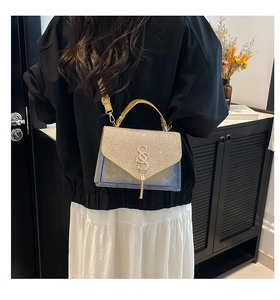 Detail of crossbody bag with gold rhinestones, blue PVC, and a metallic S-shaped logo