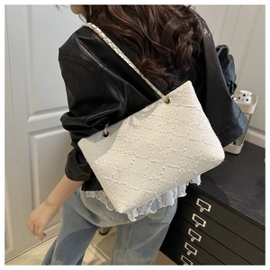 Detail of white tote bag with woven texture and leather chain strap on a model