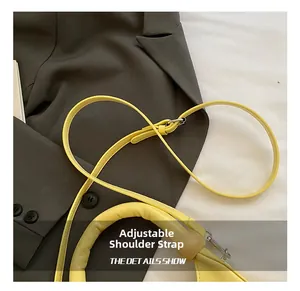Detail of adjustable leather shoulder strap and silver hardware on yellow crescent bag