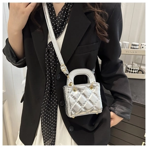 Close-up of a silver quilted leather mini bag with golden metal hardware and round handles