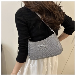 Macro shot of silver sequined shoulder bag featuring metallic bow and zipper detail