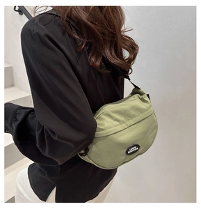 Dettaglio della borsa a mezzaluna in nylon verde avocado con tracolla nera regolabile
