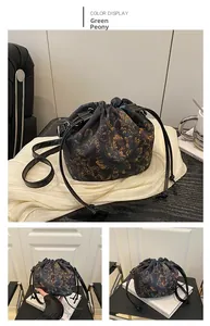 Detail of green peony print silk bucket bag with drawstring closure and crossbody strap