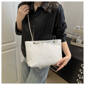 Detailed close-up of white tweed tote bag featuring metal chain strap and luxury texture