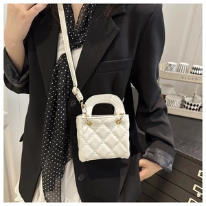 Close-up of white quilted mini crossbody bag worn by model with adjustable strap detail