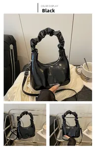 Close-up of black glossy leather bag with scrunchie handle and adjustable shoulder strap