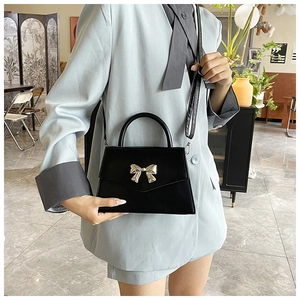 Borsa a trapezio nera alla moda con fibbia a fiocco d'argento indossata da una modella a casa