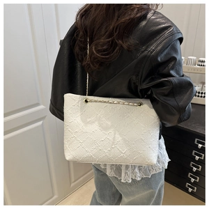 Close-up of white quilted tote bag with golden chain strap and textured fabric