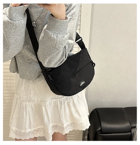 Dettaglio della borsa a tracolla minimalista a mezzaluna in nylon nero con cinturino