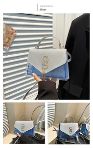 Detail of silver glitter flap bag with gold SS logo, fringe, and blue quilted texture