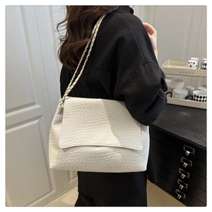 Détail d'un sac en cuir blanc tressé avec bandoulière chaîne dorée élégante sur l'épaule