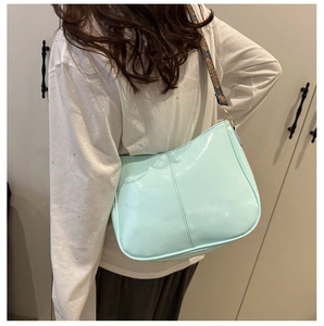 Detail of light blue hobo bag with patterned jacquard strap worn by a female model