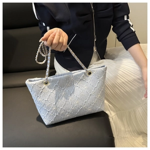 Detail of light blue checkered tote bag with 3D floral texture and gold chain strap