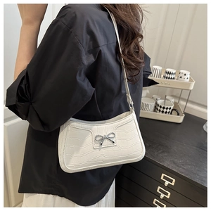 Detail of white crocodile pattern shoulder bag with a silver bow metal buckle