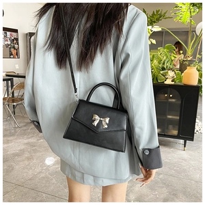 Elegante borsa nera con fiocco argento indossata su un blazer azzurro