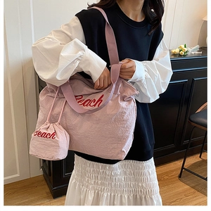 Close-up of pink canvas tote and mini pouch featuring Beach embroidery and wide strap