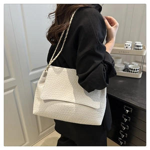 Detail view of the woven texture and metal chain strap on the white shoulder bag