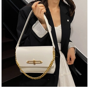 Detail of white leather shoulder bag with gold clasp and chain on model