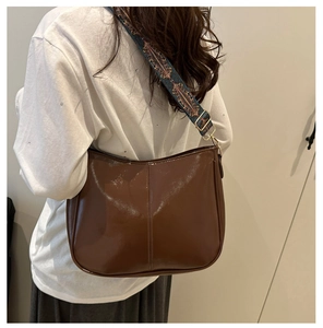 Detail of glossy brown tote bag with colorful ethnic style woven shoulder strap