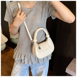 Detail of cream leather half-moon bag featuring round top handle and crossbody strap