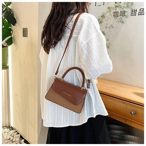 Brown leather handbag with woven texture shown on a model in a cozy cafe setting