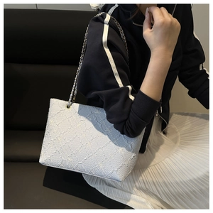 Detail of light blue embroidered tote bag featuring textured fabric and gold chain strap