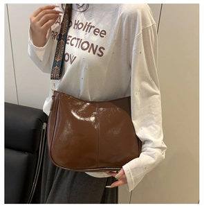 Brown glossy leather saddle bag with vintage embroidered wide strap on female model