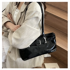 Close-up of black patent leather tote bag with silver buckle and glossy finish detail