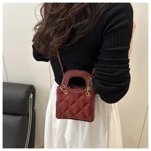 Detail view of burgundy quilted leather handbag with gold hardware and top handle