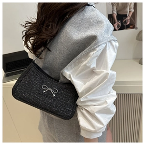 Detailed view of black glitter shoulder bag with silver bow buckle on model