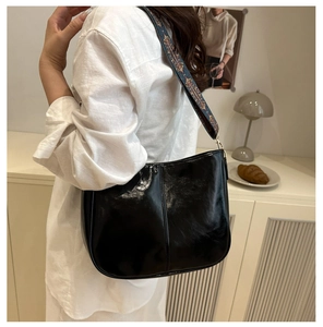 Polished black faux leather tote with bohemian blue and gold embroidered strap on model
