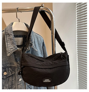 Detail of black nylon crescent moon fanny pack with Lucky Fashion logo on denim jacket