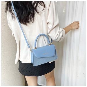 Sky blue textured handbag with gold lettering shown on shoulder for daily commute