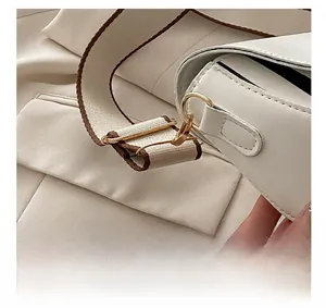 Gros plan détaillé du fermoir doré et de la bandoulière tissée beige du sac chic