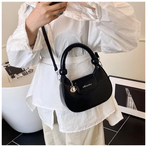 Close-up of black leather hobo bag featuring silver charm and removable shoulder strap