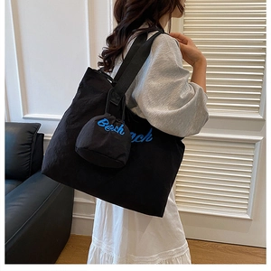 Detail of black corduroy shoulder bag with blue Beach embroidery and matching drawstring pouch