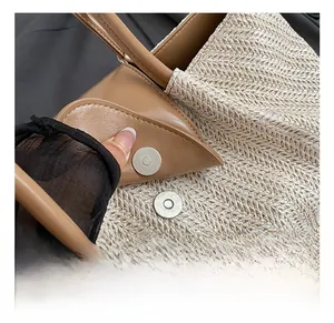 Detailed macro view of silver magnetic buckle and brown leather trim on woven tote bag