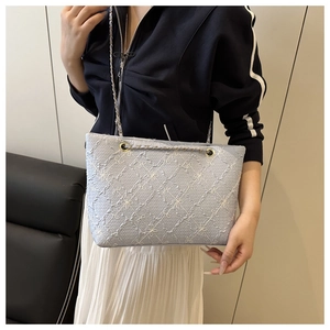 Détail d'un sac à bandoulière bleu clair avec broderie florale et chaîne argentée