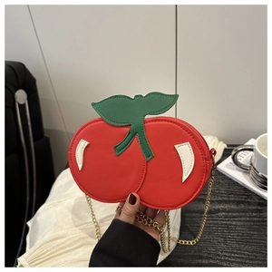 Detailed view of creative red cherry shaped crossbody bag with green leaf and gold chain